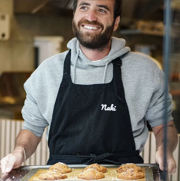 Ilan, souriant, avec une plaque de pâtisseries